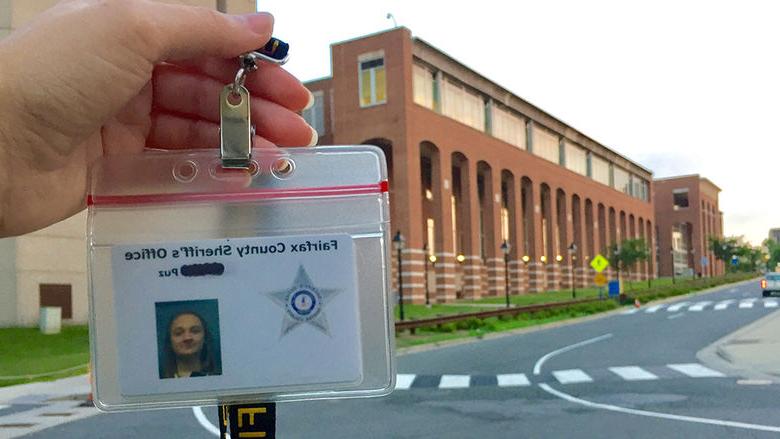 Alexis Puz displays her internship ID in front of the Fairfax County Sherrif's Office